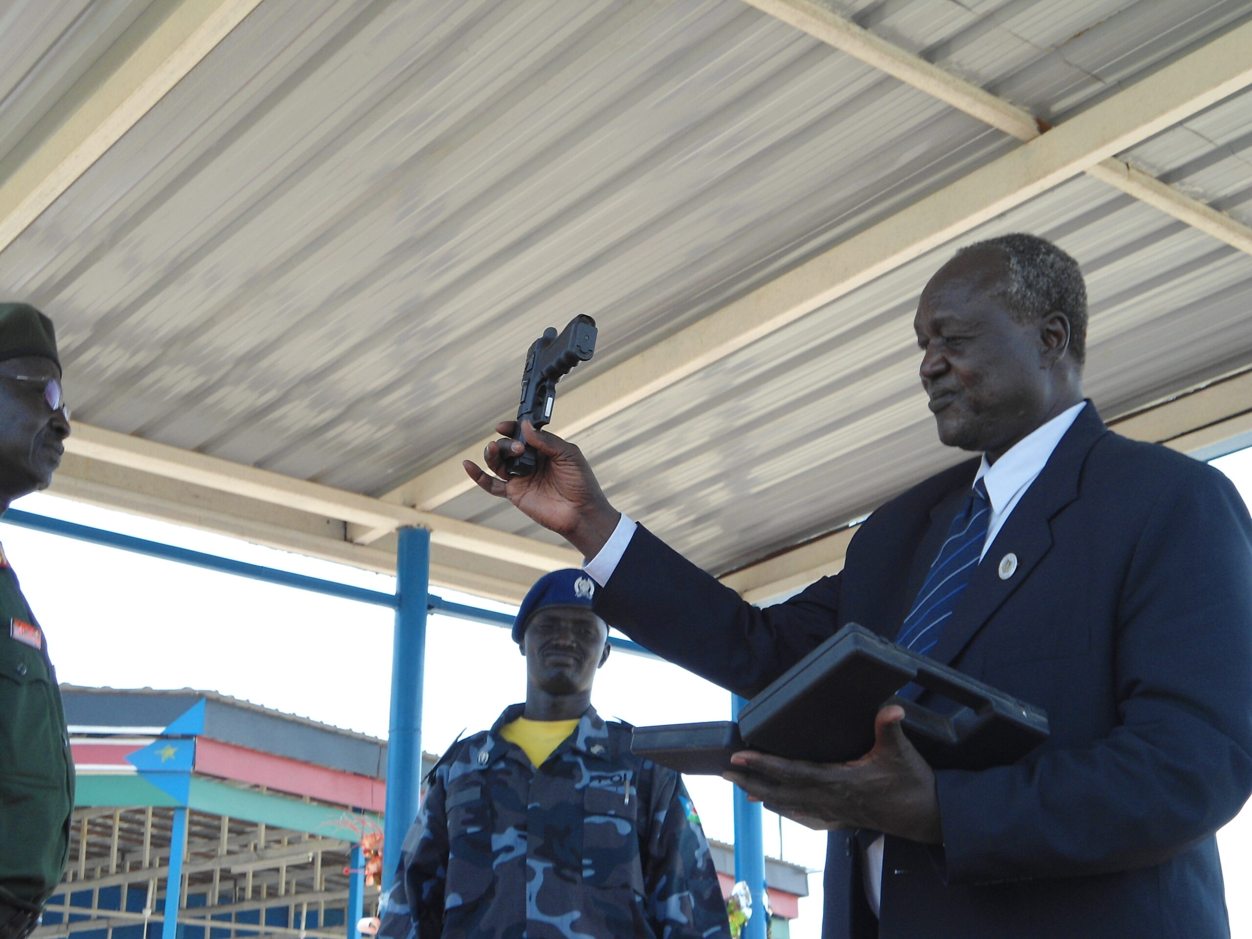 Governor of Jonglei State, Kuol Mayang Juuk, showing his pistol to the public before handing it to Gen. Kuol Dim in Bor Freedom Square to mark the start of the disarmament campaign. March 12, 2012 (ST)