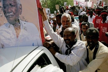Sudanese men mourn next to a poster of Ibrahim Nugud, late leader of Sudan's Communist party, during his funeral in Khartoum on March 25, 2012 (GETTY)
