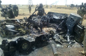 Sudanese troops stand next to a burnt out vehicle in Sudan's southern oil centre of Heglig on March 27, 2012 (AFP)
