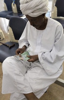 FILE - A person counts after receiving the new Sudanese currency from a cashier at a branch of the central bank of Sudan in Khartoum July 24, 2011 (Reuters)