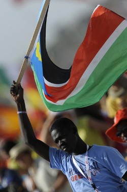 A pilgrim waves a flag of South Sudan as he attends a mass celebrated by Pope Benedict XVI on a vast dusty esplanade outside Madrid during the World Youth Day (WYD) festivities on August 21, 2011. (Getty)