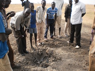 Civilians at a cluster-bomb crater in Thaon village, near Bentiu, Unity state, South Sudan, April 12, 2012 (ST)