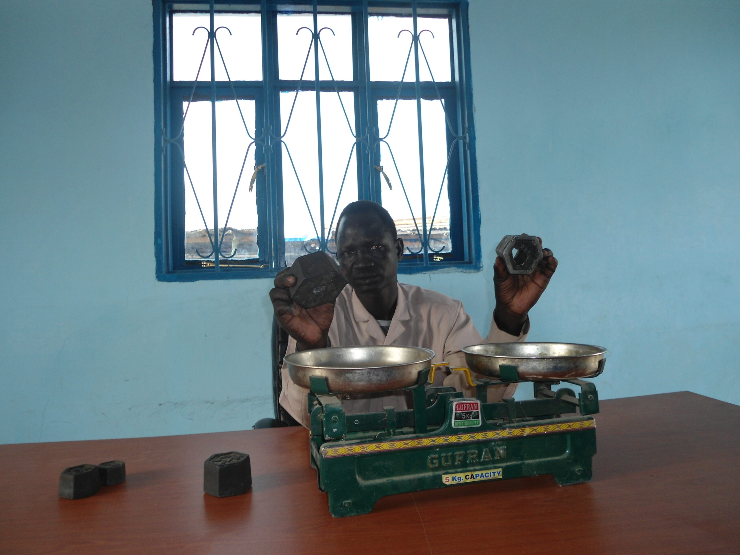 Dircetor of Grades and Standard Measures, Anyuon Deng, showing the right weighing stone in his left hand and a faulty weighing stone in his right hand  in his office in Bor Marol Market, 27 April 2012 (ST)