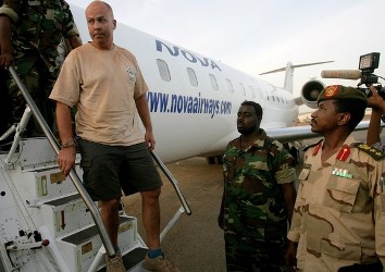 One of the four foreigners captured in Heglig on April 28, 2012, is escorted off an airplane by Sudanese soldiers in Khartoum while SAF spokesperson Sawarmi Khaled, on the right, looks to them (Getty)