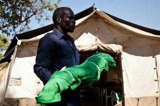 A man carries the body of a two year old girl at the Yida refugee camp nutrition center and hospital in Yida, South Sudan, on April 26, 2012 (AFP)