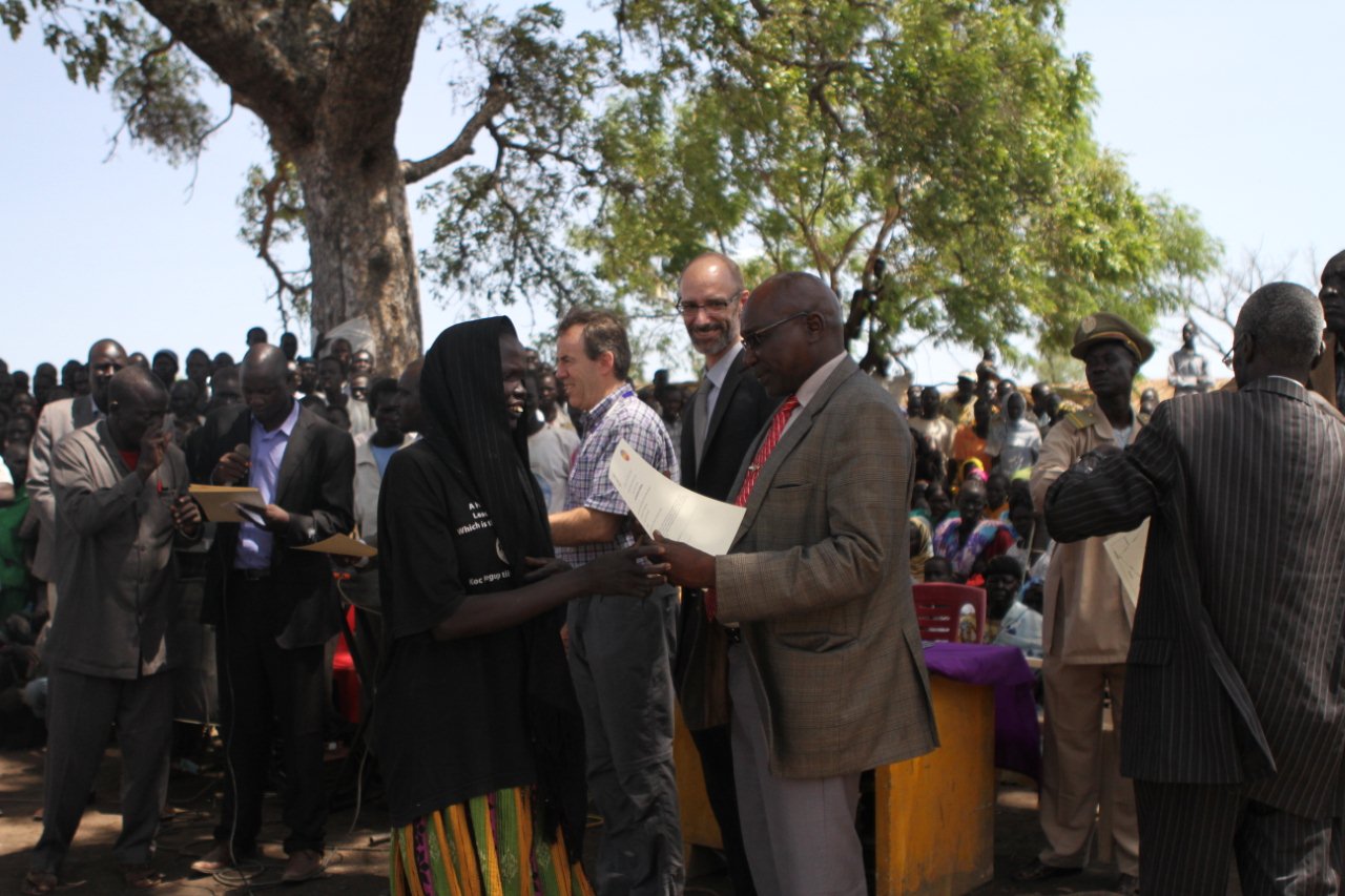 George Conway, the UNDP country director and Paul Malong Awan, the Northern Bahr el Ghazal state governor present a land certificate to a returnee in Aweil, May 24, 2012 (M. Nowak/UNDP)