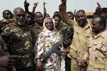 In this Tuesday, April 24, 2012 photo, Sudanese state Minister of Information Sana Hamad poses for a photo with Sudanese armed forces at the oil-rich border town of Heglig, Sudan (AP)