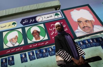 A Sudanese woman stands in front of an electoral poster for Sudan’s ruling National Congress Party (Guardian)