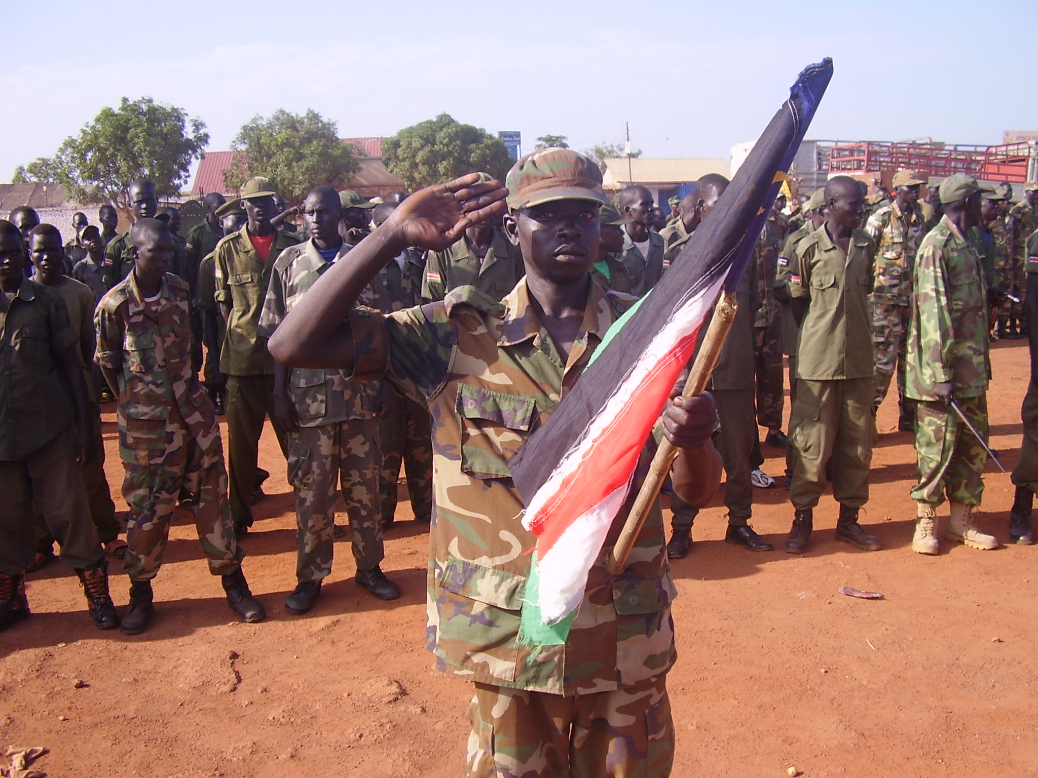 SPLA soldier holds up a South Sudan flag as he salutes arriving officers and State W. Bahr el Ghazal Governor at Independence Celebrations in Wau, 9 July 2012 (ST)