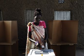 A Sudanese woman casts her ballot at an outdoor polling station in the village of Dulab in Upper Nile state, April 12, 2010 (Reuters)