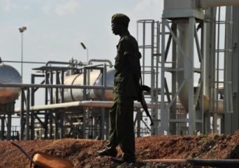 A South Sudanese soldier walks past a crude oil reservoir tank at a field processing facility in Unity State on November 10, 2010. (Getty)