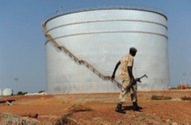 A Southern Sudanese soldier walks past a crude oil reservoir tank at a field processing facility in Unity State on November 10, 2010. (AFP)
