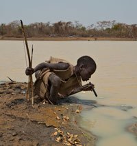 A young goat herder prepares to drink dam water through a filtration pipe provided by The Carter Center’s Guinea worm eradication program. (Photo: The Carter Center/L. Gubb)