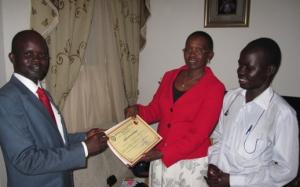 Madame Angelina, President of the newly-formed IofC South Sudan, receives the certificate of registration from the lawyer, watched by another member Tongo James Elisama (Photo: Mike Brown)