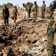 Southern army officers in Northern Bahr el Ghazal state in Sudan, peer into a bomb crater created from one of the bombs dropped by the northern Sudanese army on a southern army base in the disputed border zone of Kiir Adem, where Southern Sudan meets Darf (VOA)
