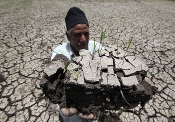 An Egyptian farmer holds a handful of soil to show the dryness of the land due to drought in a farm formerly irrigated by the river Nile, in Al-Dakahlya, about 120km from Cairo, on 13 June 2013 (Photo: Reuters/Mohamed Abd El Ghany)