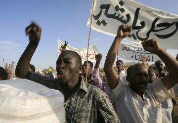 Holding a banner that reads in Arabic, 