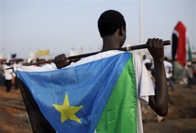 A youth holds the South Sudanese flag as he waits for the start of independence celebrations in the capital, Juba, on 9 July 2011 (AP)