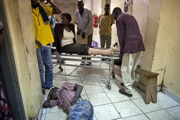 A female patient with a broken leg gets moved past an injured man on the floor at the emergency ward at the Juba Teaching hospital, which has a shortage of beds, on 19  July 2012 (Photo: Paula Bronstein/Getty Images)