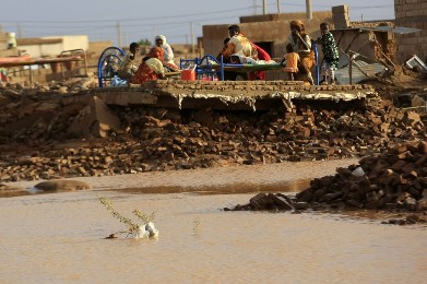 Family members rest in the remains of their house destroyed by floods caused by heavy rains in Khartoum on 6 August 2013 (Photo: Reuters/Mohamed Nureldin Abdallah)