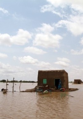 A Sudanese woman stands next to her house in the middle of a flooded street on the outskirts of the capital Khartoum on August 10, 2013 (ASHRAF SHAZLY/AFP/Getty Images)