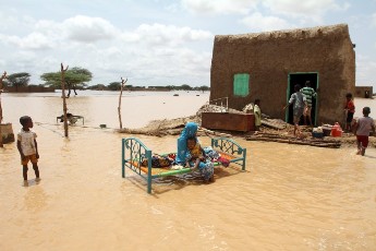 A Sudanese woman sits with her child next to her house in a flooded street on the outskirts of the capital Khartoum on 10 August 2013 (Photo: Ashraf Shazly/AFP/Getty Images)