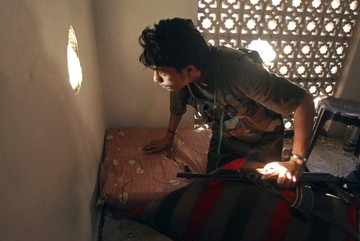 A Free Syrian Army fighter peers through a hole in a wall in Aleppo's Salaheddine neighbourhood August 12, 2013 (REUTERS/Ammar Abdullah)