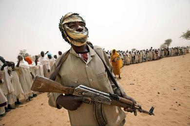 A member of the rebel Sudan Liberation Movement/Abdul Wahid stands guard as people stand in line behind him for the arrival of an UNAMID delegation to open a new clinic in Forog, north Darfur in this May 30, 2012 (Albert Gonzalez Farran/UNAMID/Handout via Reuters)