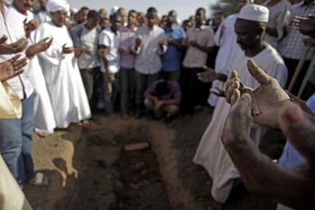 FILE - In this Saturday, Sept. 28, 2013 file photo, Sudanese men pray over the body of Salah Sanhory, 26, who was killed on Friday Sept. 27, 2013 by security forces, during his funeral in Khartoum, Sudan (AP Photo/Khalil Hamra, File)