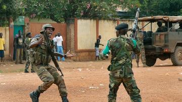 A FOMAC regional peacekeeper screams for a ceasefire as troops fire their guns to secure the evacuation of Muslim clerics from the St Jacques Church in Bangui, Central African Republic, Thursday Dec. 12, 2013 (AP Photo/Jerome Delay)