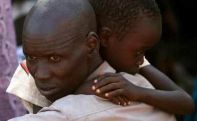 An internally displaced man holds his son inside a UN compound in Juba on 19 December 2013 (Photo: Goran Tomasevic/Reuters)