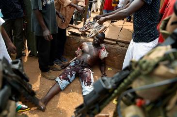 FILE - In this Monday, Dec. 9, 2013 file photo, a suspected member of a Christian militia Sincere Banyodi, 32, lays wounded by machete blows in the Kokoro neighborhood of Bangui, Central African Republic (AP Photo/Jerome Delay, File)