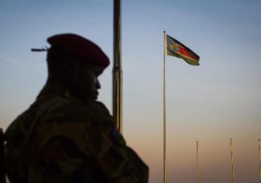 A government soldier stands guard as a South Sudanese flag flies in the background, at the memorial to leader John Garang, in Juba, on Monday January 13, 2014. (Photo AP/Mackenzie Knowles-Coursin)