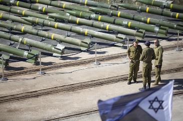 Israeli naval officer stand next to dozens of rockets on display after being seized from the Panama-flagged KLOS C civilian cargo ship that Israel intercepted last Wednesday off the coast of Sudan, at a military port in the Red Sea city of Eilat, southern Israel, Monday, March 10, 2014 (AP Photo/Ariel Schalit)