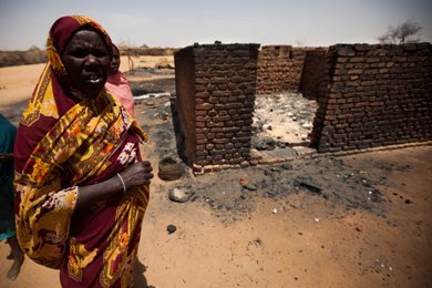 A Darfurian woman stands outside a burnt house in Mellit on 25 March 2014 (Photo: UNAMID/Albert Gonzalez Farran)