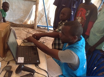 A UNHCR staffer scans the fingerprints of a South Sudanese refugee child into its database at the Zawanzi transit camp in Uganda's Adjumani district on 19 March 2014 (ST)