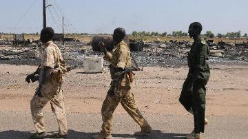 Soldiers from the South Sudanese army (SPLA) patrol near burnt houses in Unity state capital Bentiu on 12 January 2014 (Photo: AFP/Simon Maina)