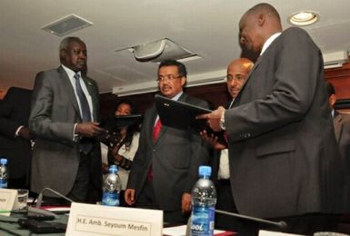 Nhail Deng Nhail (left), the head of South Sudan's negotiating team, and top rebel negotiator Taban Deng Gai (right) sign a cessation of hostilities agreement in front of mediator Ethiopian foreign minister Tedros Adhanom in the Ethiopian capital, Addis Ababa, on 23 January 2014 (AP)