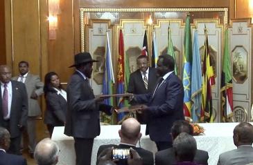 South Sudan's president Salva Kiir (L) and rebel leader Riek Machar (R) exchange the signed documents after reaching a peace agreement in the Ethiopian capital, Addis Ababa, on 9 May 2014 (AP)