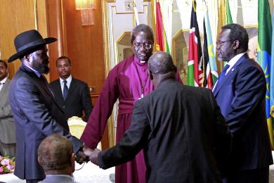 South Sudan's president, Salva Kiir (L), and rebel leader Riek Machar (R) shake hands and pray before signing a ceasefire agreement aimed at ending conflict in the country in the Ethiopian capital, Addis Ababa, on 9 May 2014 (Photo: AP/Elias Asmare)