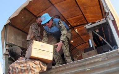 UNMISS peacekeepers distribute boxes of food to displaced South Sudanese people on 22 December 2013 (AFP)