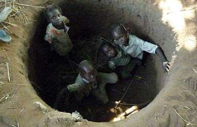 Children in South Kordofan's town of Kauda take cover from a passing Antonov in a makeshift bomb shelter in 2012 (Photo: Peter Moszynski)