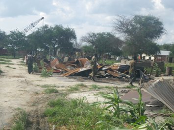 Soldiers from the South Sudanese army (SPLA) inspect destroyed homes in Duk county’s Poktap on 17 July 2014 (ST)