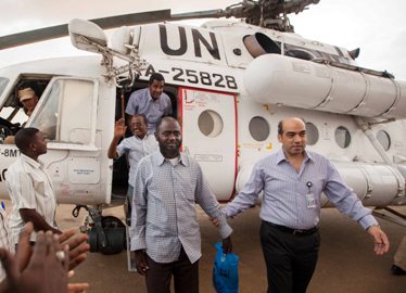 A member of the joint UN-African Union Mission in Darfur (UNAMID), right, escorts three freed humanitarian workers after landing in El Fasher, North Darfur on 19 July 2014 (Photo: UNMAID/Albert Gonzalez Farran)