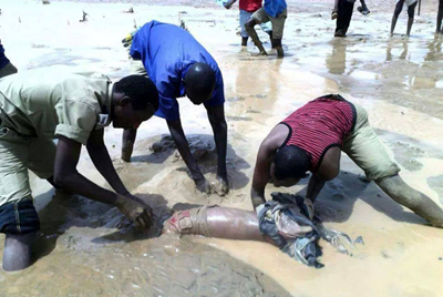 مواطنون ينتشلون جثة من الأوحال بعد أن جرفتها السيول غربي الخرطوم في أغسطس 2014