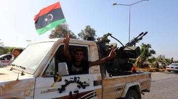 An Islamist fighter from the Fajr Libya (Libyan Dawn) coalition flashes the V sign for victory at the entrance of Tripoli international airport on 24 August 2014 (Photo: AFP/Mahmud Turkia)