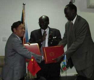 Chinese Ambassador to South Sudan Ma Qiang (L) exchanges copies of the signed agreement on economic and technical cooperation with undersecretary for the ministry of foreign affairs Charles Manyang (R) as foreign affairs minister Barnaba Marial Benjamin applauds in Juba on 5 September 2014 (ST)