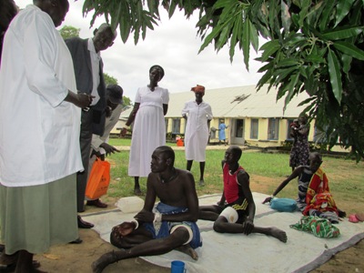 Bor county commissioner Agot Alier Leek (C) visits wounded youths referred to Bor hospital as health workers look on on 28 October 2014 (ST)