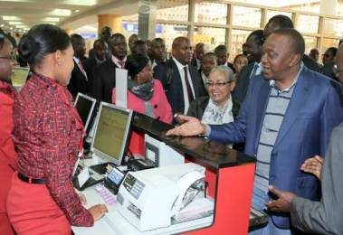Kenyan President Uhuru Kenyatta (2nd-R) and First Lady Margaret Kenyatta check in alongside other passengers at Nairobi airport as they head to the Hague on October 7, 2014 (Photo AFP-PSCU)