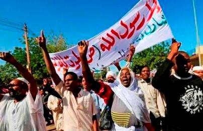Protesters shout slogans against France and call for an apology while carrying banners during a demonstration against satirical French weekly Charlie Hebdo after Friday prayers in Khartoum on 16 January 2015. The banner reads: 